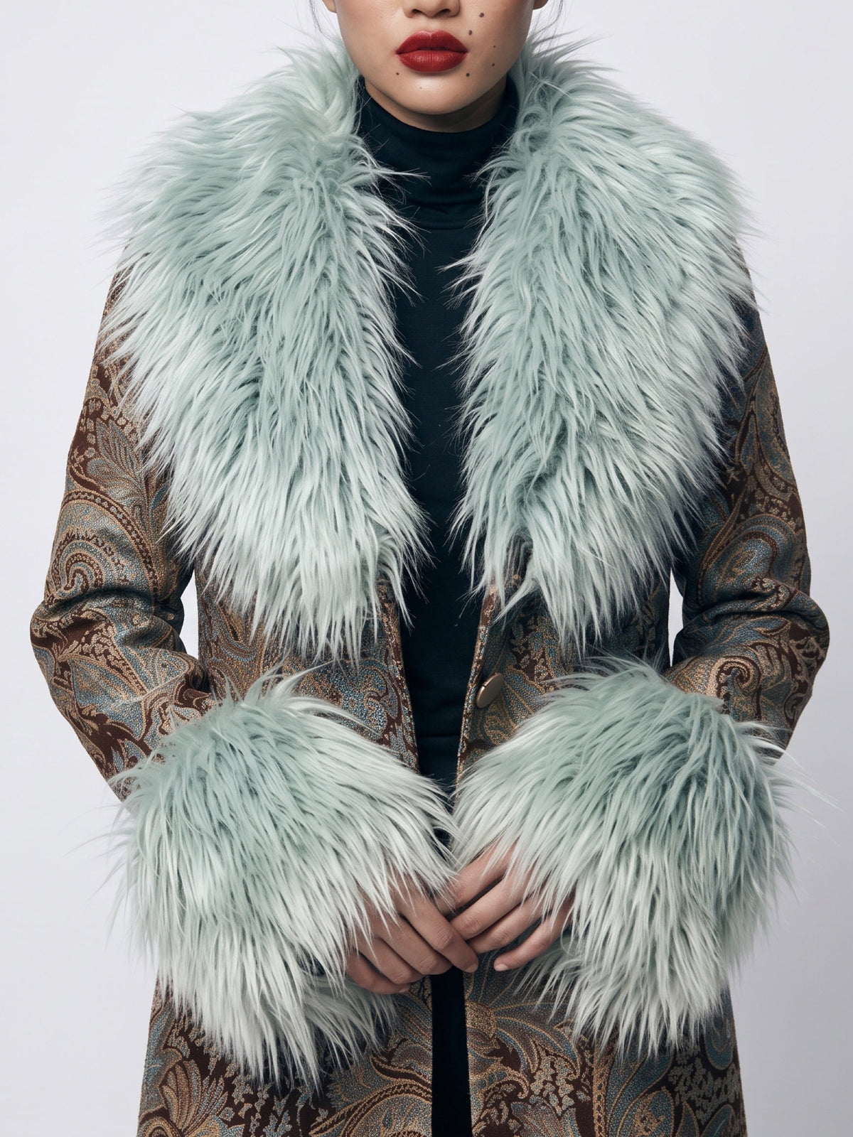 Luxury dramatic fur  trim icy blue / green shearling long shaggy soft fur cuffs and collar are featured in this closeup photo of a paisley blue brown gray penny lane 70s style duster tapestry coat . 
